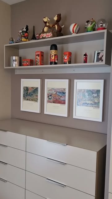 Beyaz çekmeceli dolap, raflar ve çerçeveli resimler